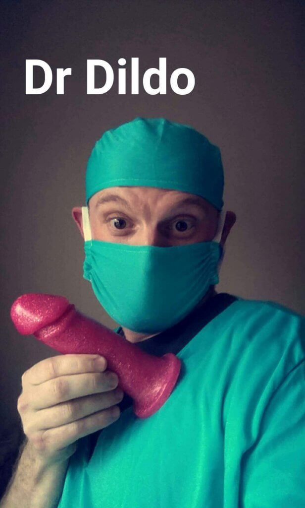 Adam in a medical mask, hat and gown holding an Adam Dildo
