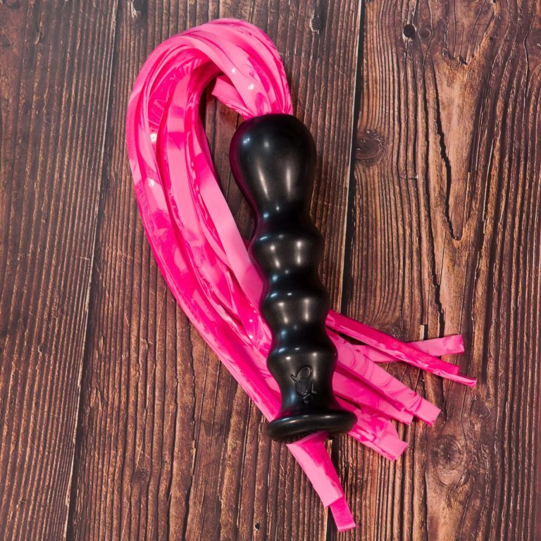 Godmeiche Resin Flogger Handle Pink SIlicone Falls on Wood Background